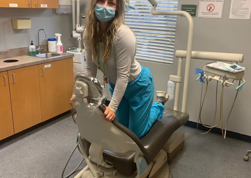 Cassidy kneeling on the dental chair
