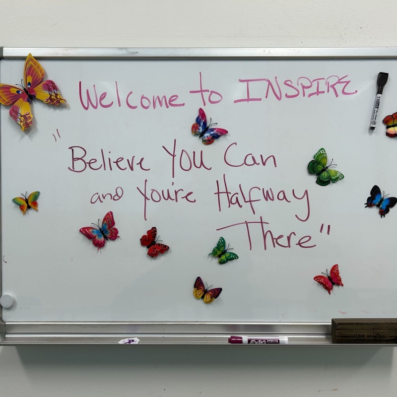 A white board at the INSPIRE Clinic that reads "Believe you can and you're halfway there."