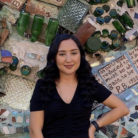 Nancy Arellano standing in front of a wall with glass bottles used as art.