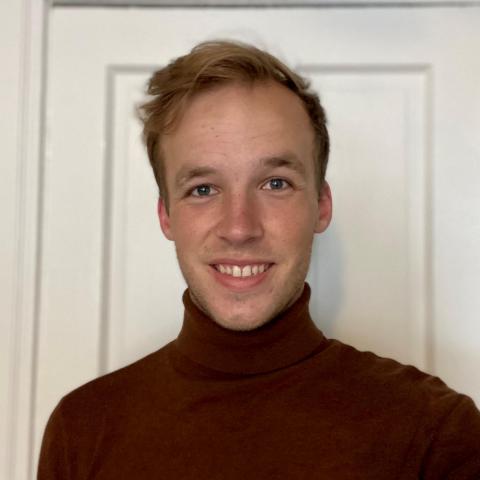 John Hansen is facing the camera and smiling. He is wearing a burgundy turtle neck.