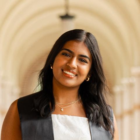Anoushka stands in the middle of the frame, facing the camera and smiling.