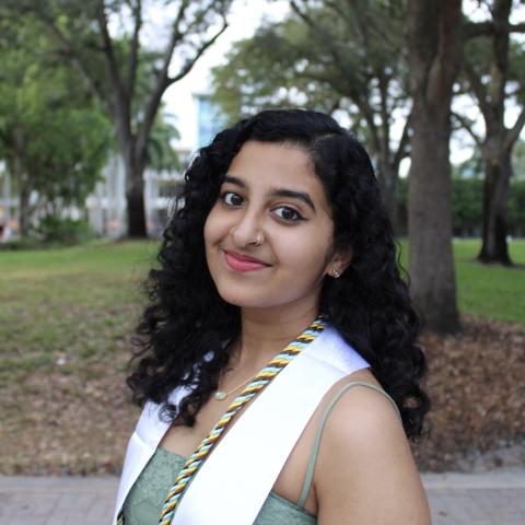 Meena stands in the middle of the frame, smiling at the camera.