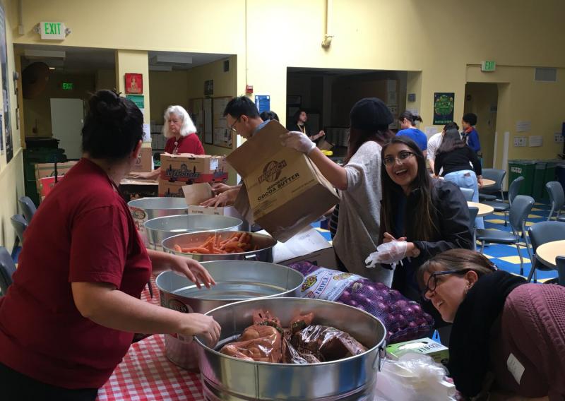 Neha Chhabra smiling as she prepares to unload a sack of onions into a bucket at the Curry Senior Center inaugural Food Pharmacy.