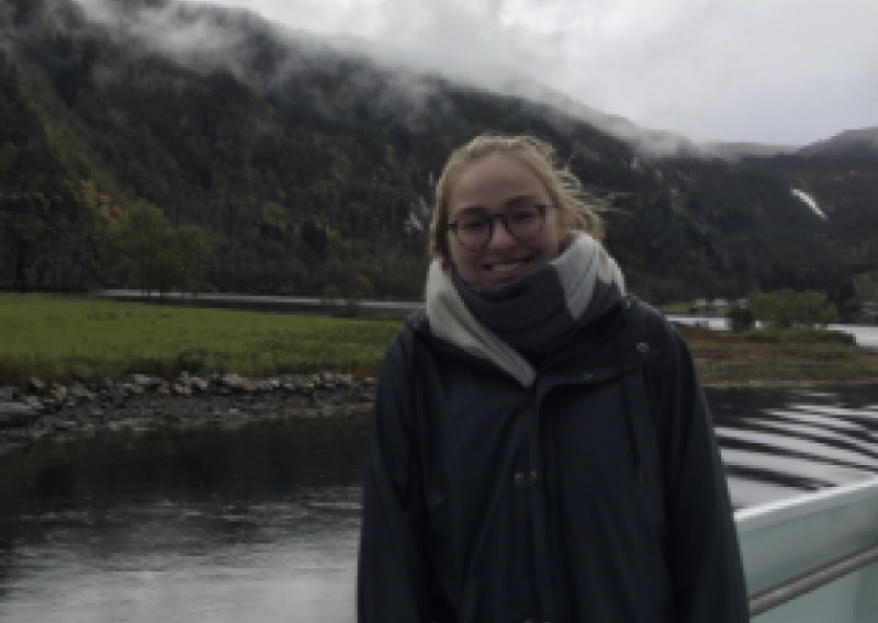 NHC PGH member Bethany smiling on a boat with mountains and water in the background