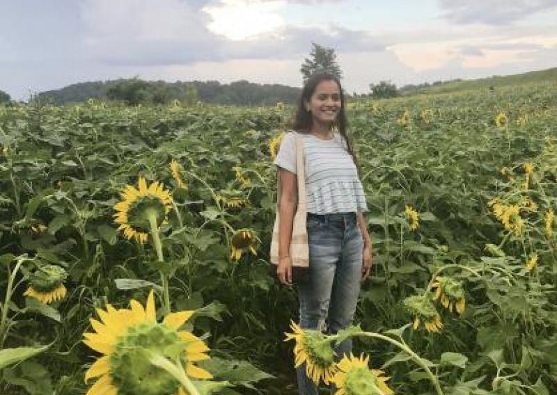 NHC PGH member Roosha smiling in a sunflower field