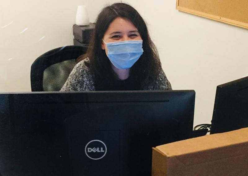 Charlotte Kishi sitting behind a desk, with two computer monitors in front of her.