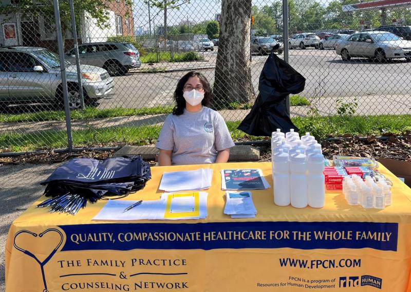 Amal sitting a table handing out resources for community members