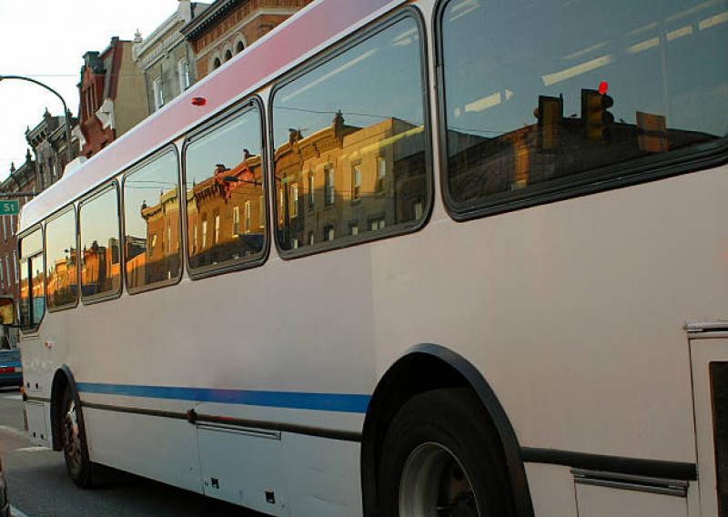 the side of a bus with row homes showing in the reflection of the windows