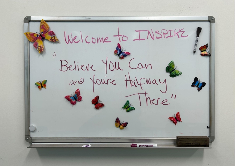 A white board at the INSPIRE Clinic that reads "Believe you can and you're halfway there."