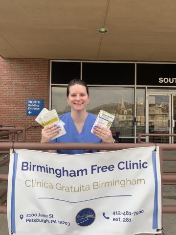 Aurelia is sitting behind a Birmingham Free Clinic sign.