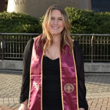Leila in front of a sculpture in a graduation gown