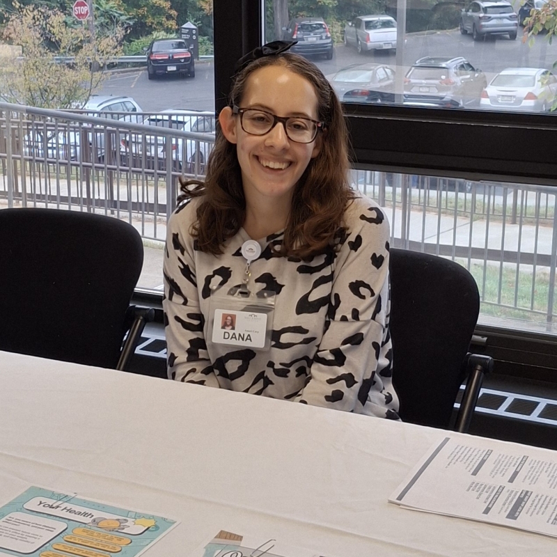 Dana Scandura is sitting at an information table at a health fair.