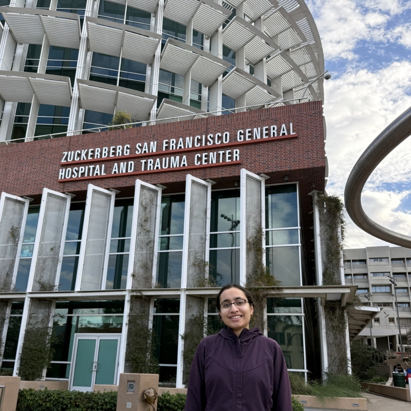 Abeerah stands in the bottom the frame, with the entrance to Zuckerberg San Francisco General behind her.