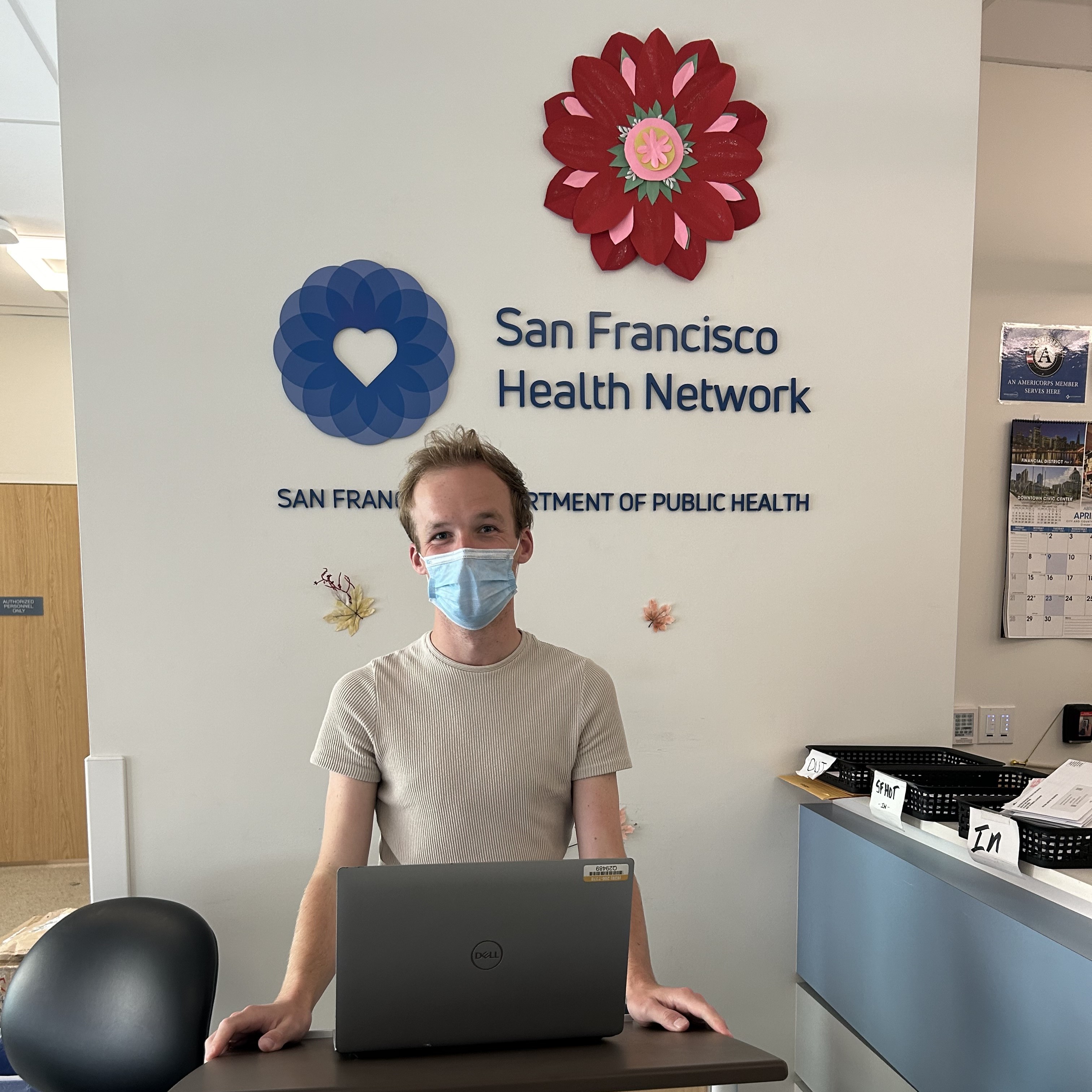 ​John Hansen is standing and facing the camera. Behind them is the San Francisco Health Network logo. [Click and drag to move] ​