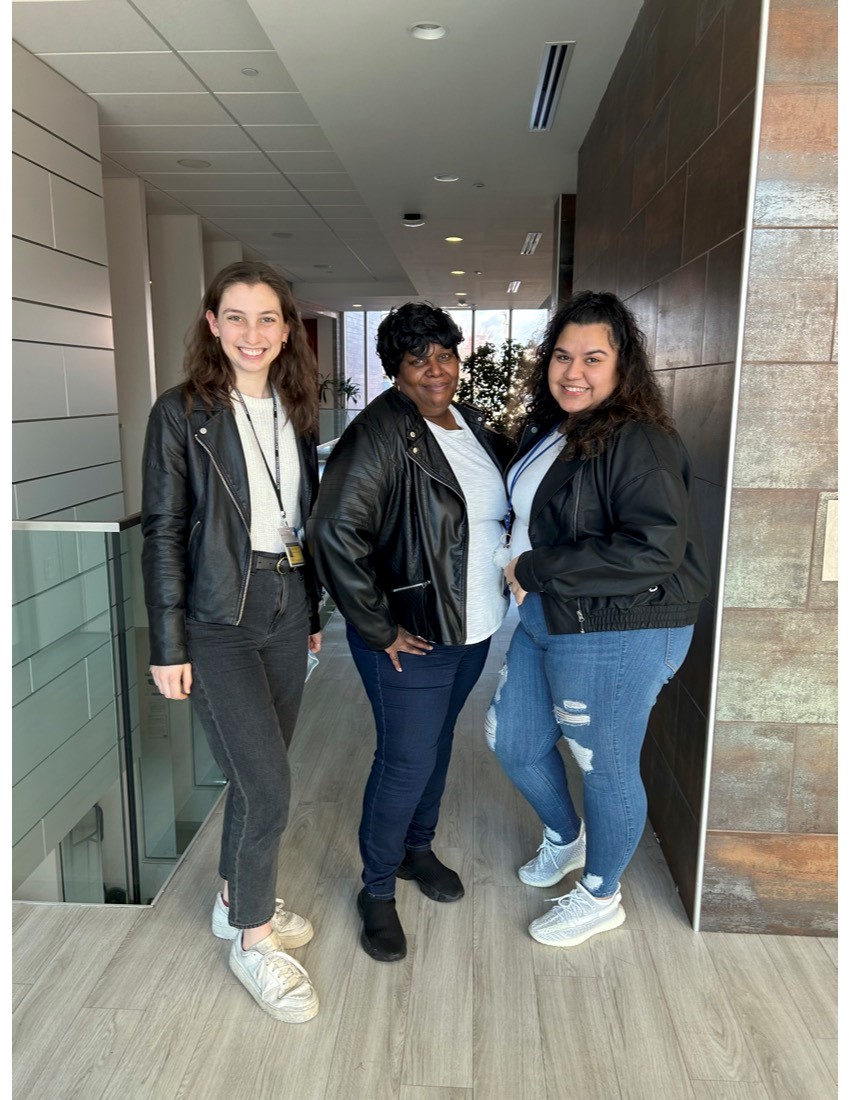 Three people standing next to each other smiling and all wearing black leather jackets